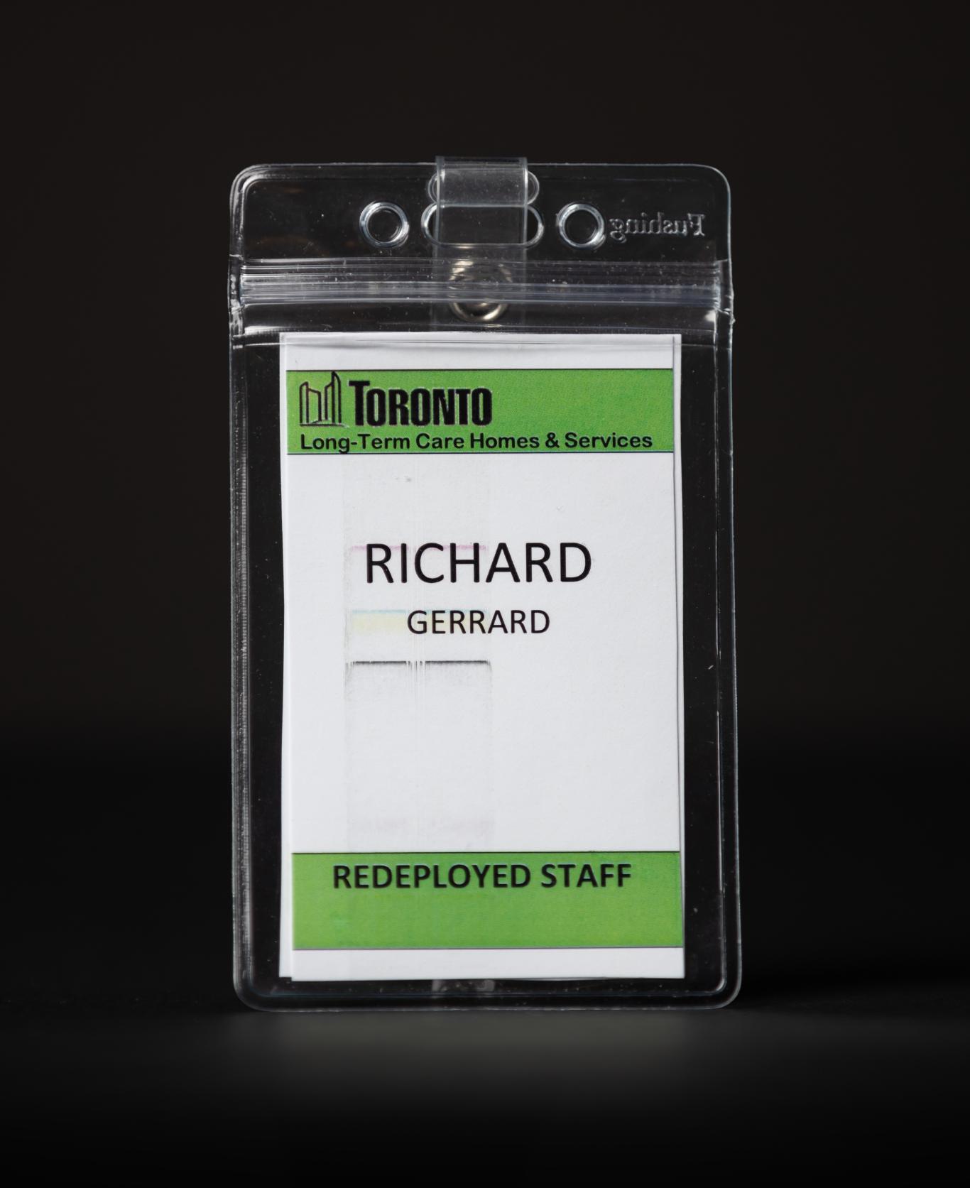 A vertical paper badge with the name “Richard Gerrard” printed on it.