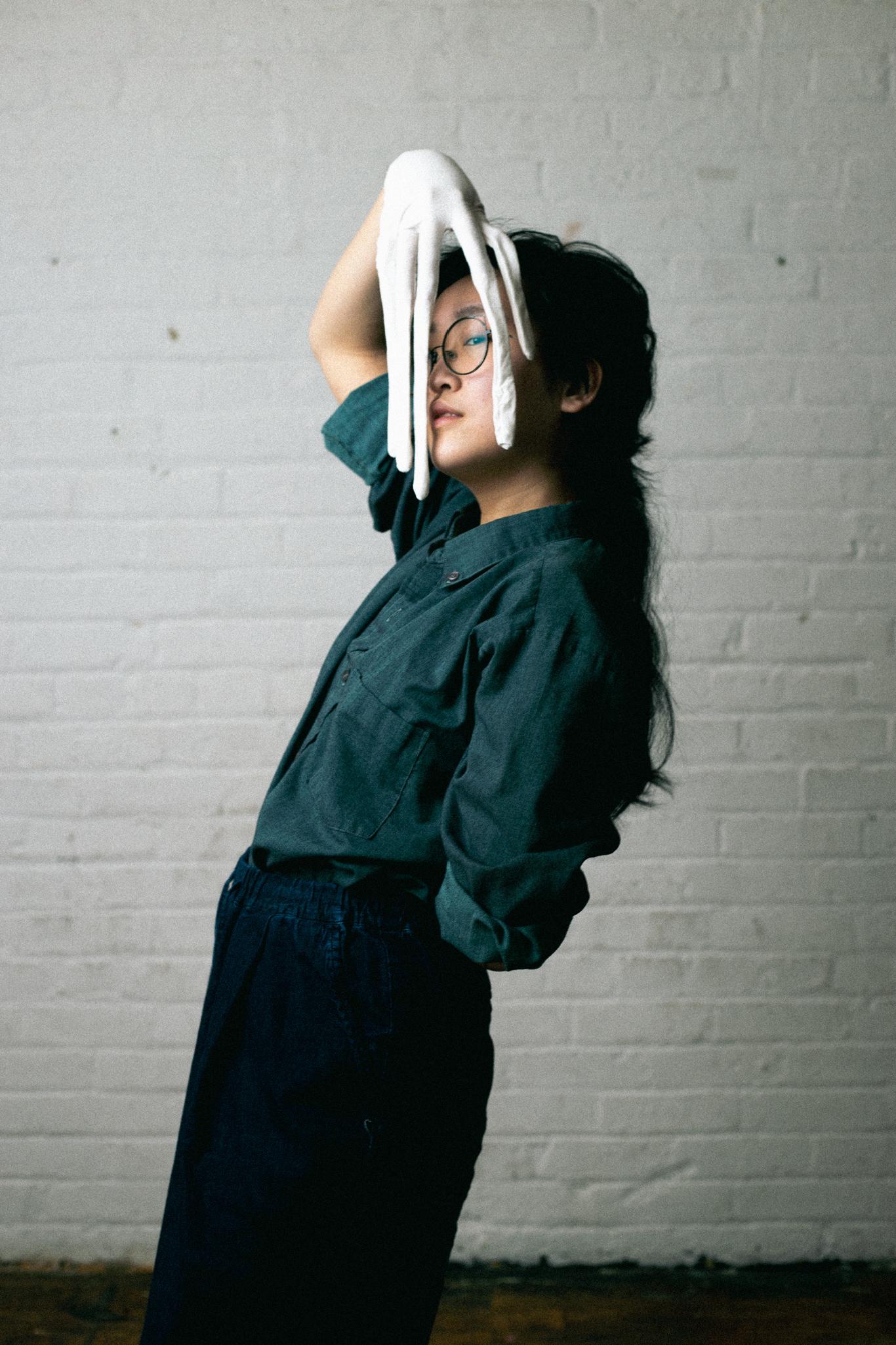 A portrait of a person of Cantonese descent with a white glove draped on their face.