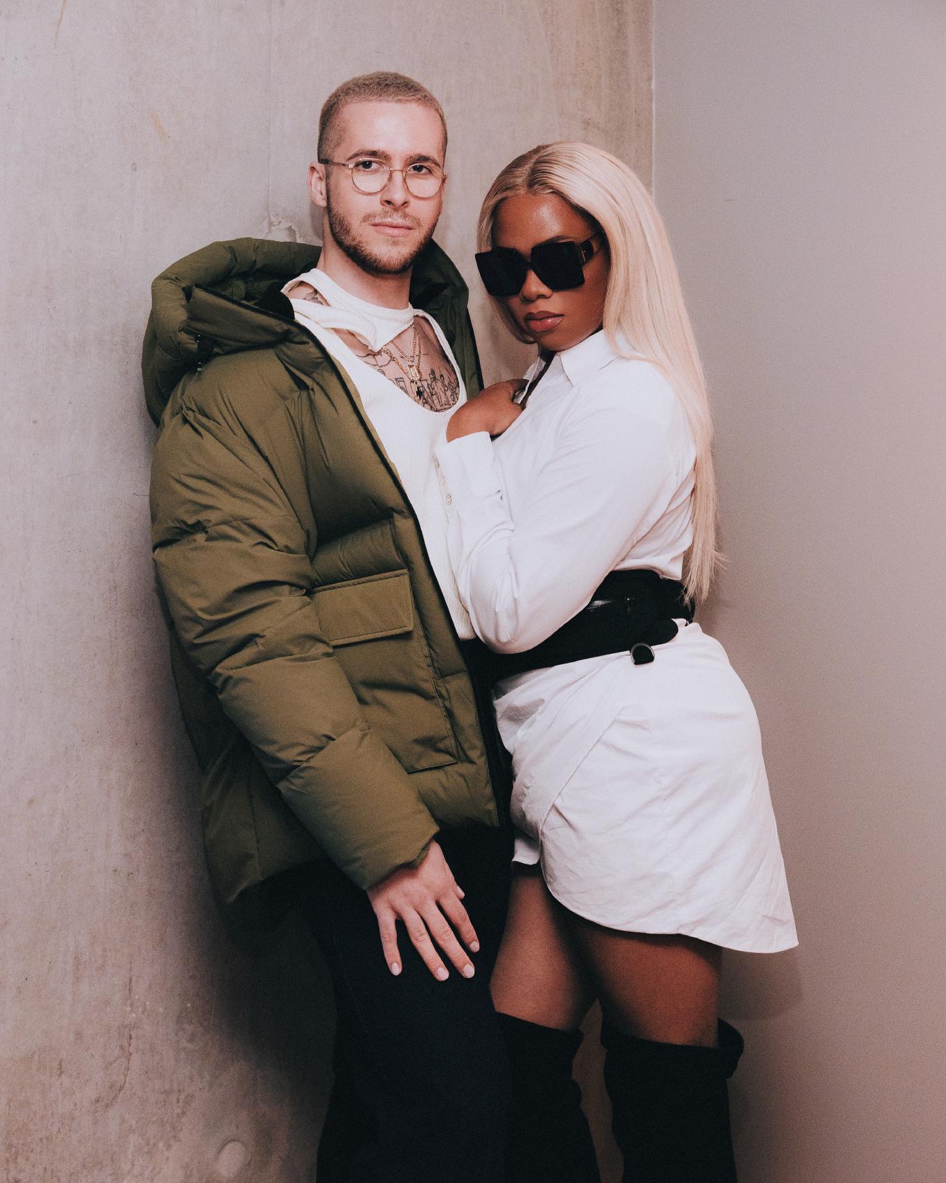 A studio portrait of a Black woman and White person in a half hug